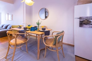 A dining area with a wooden table, four wicker chairs, a round mirror, and a hanging light fixture.