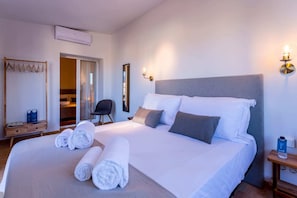 Une chambre d’hôtel avec un grand lit, une table de chevet en bois, un miroir et une chaise.