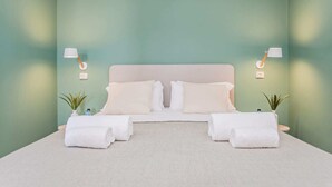 A neatly made bed with white linens and pillows, two bedside tables with lamps, and two potted plants. - Sweett | Rocafort Atic 3 (Barcelona)