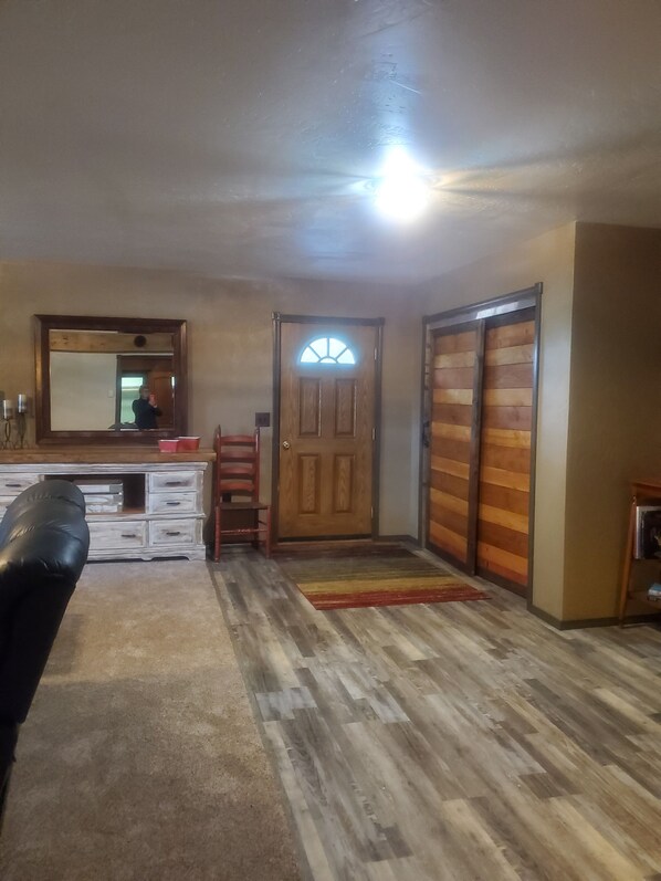 A room with a wooden door, a mirror, a desk, and a black leather chair.