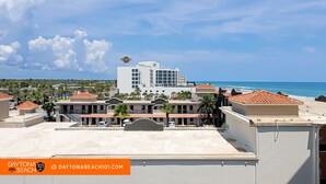 A hotel with a view of the beach, featuring a large building with a sign, multiple balconies, and a clear sky. - Beachfront Studio on Daytona Beach w/ Oceanfront Pool & Free Parking (Daytona Beach)