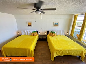 A room with two beds, a ceiling fan, and a window with curtains. - Beachfront Studio on Daytona Beach w/ Oceanfront Pool & Free Parking (Daytona Beach)
