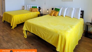 Two twin beds with yellow bedding, white pillows, and a small table with a lamp between them. - Beachfront Studio on Daytona Beach w/ Oceanfront Pool & Free Parking (Daytona Beach)