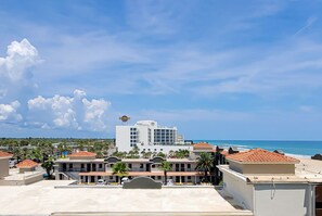 Un hôtel avec vue sur la plage, caractérisé par un grand bâtiment portant une enseigne, de nombreux balcons et un ciel dégagé.
