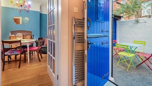A room with a dining table, chairs, a chandelier, and a blue door leading outside. - Colourful, Quirky Artist-Owned 3 Bed Next to Cafes - Pass the Keys (Belfast)