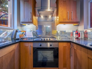 Une cuisine moderne avec des meubles en bois, une cuisinière en acier inoxydable et un dosseret carrelé.