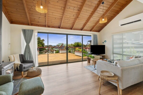 A spacious living area with a large sliding glass door to a deck, a flat-screen TV, and a cozy seating arrangement.