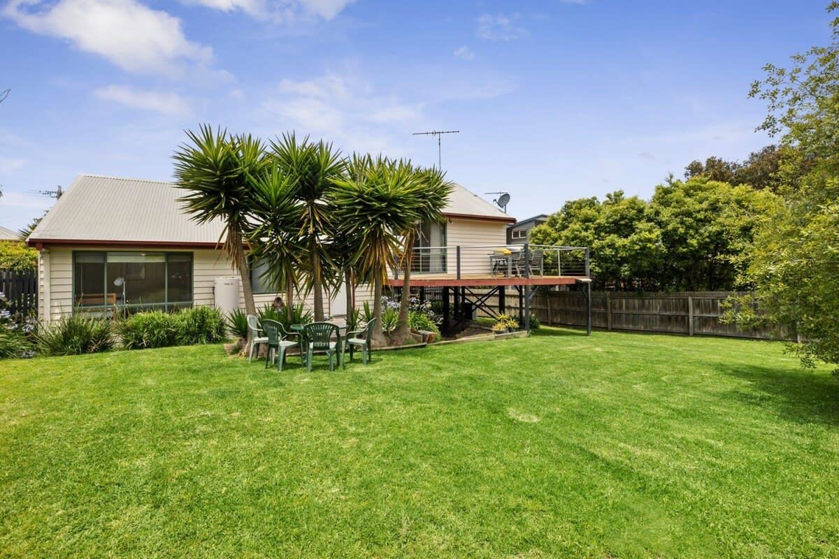 A residential house with a well-maintained lawn, a patio area with chairs, and a satellite dish.