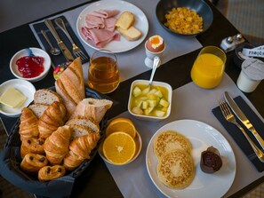 A breakfast table with croissants, fruit, pancakes, and a variety of spreads. - Hôtel De Wimereux (Wimereux)