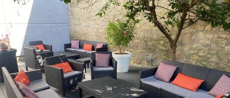 An outdoor patio with wicker furniture, including sofas and chairs, and a central coffee table.