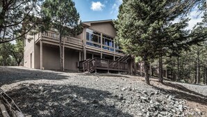 A two-story building with a balcony and a gravel driveway. - Cozy Timbers by Ruidoso Vacation Rentals (Ruidoso)