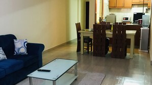 Ein Wohnzimmer mit einer Couch, einem Glastisch und einem Essbereich mit Tisch und Stühlen.