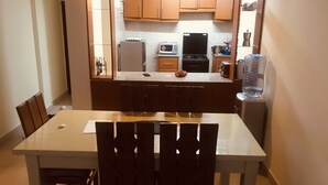 Eine kleine Küche mit Holzausstattung, einem Kühlschrank, einer Mikrowelle und einem Herd.