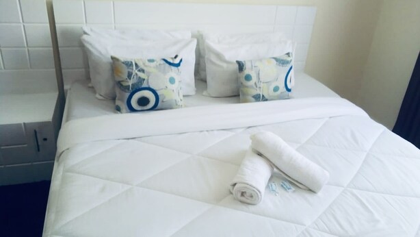 Ein Hotelzimmer mit einem Bett, weißer Bettwäsche und zwei dekorativen Kissen mit blauen und weißen Mustern.