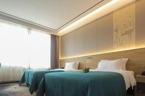 Una habitación de hotel con dos camas, un ventanal con cortinas, una obra de arte colgada en la pared y una mesita de noche con lámpara.