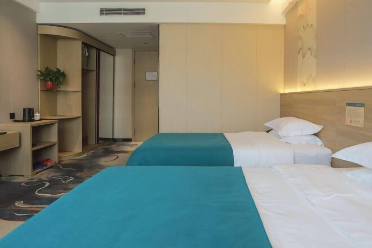 Habitación de hotel con dos camas, un escritorio y un pequeño rincón de descanso.