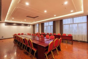 A conference room with a long table and red chairs, large windows, and a wooden floor. - Tianyue Fengya Hotel (Fan County)
