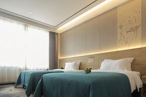 Habitación de hotel con dos camas, un ventanal grande y un mural en la pared.