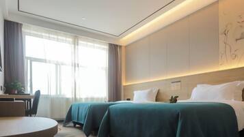 A hotel room with two beds, a desk, and a chair.
