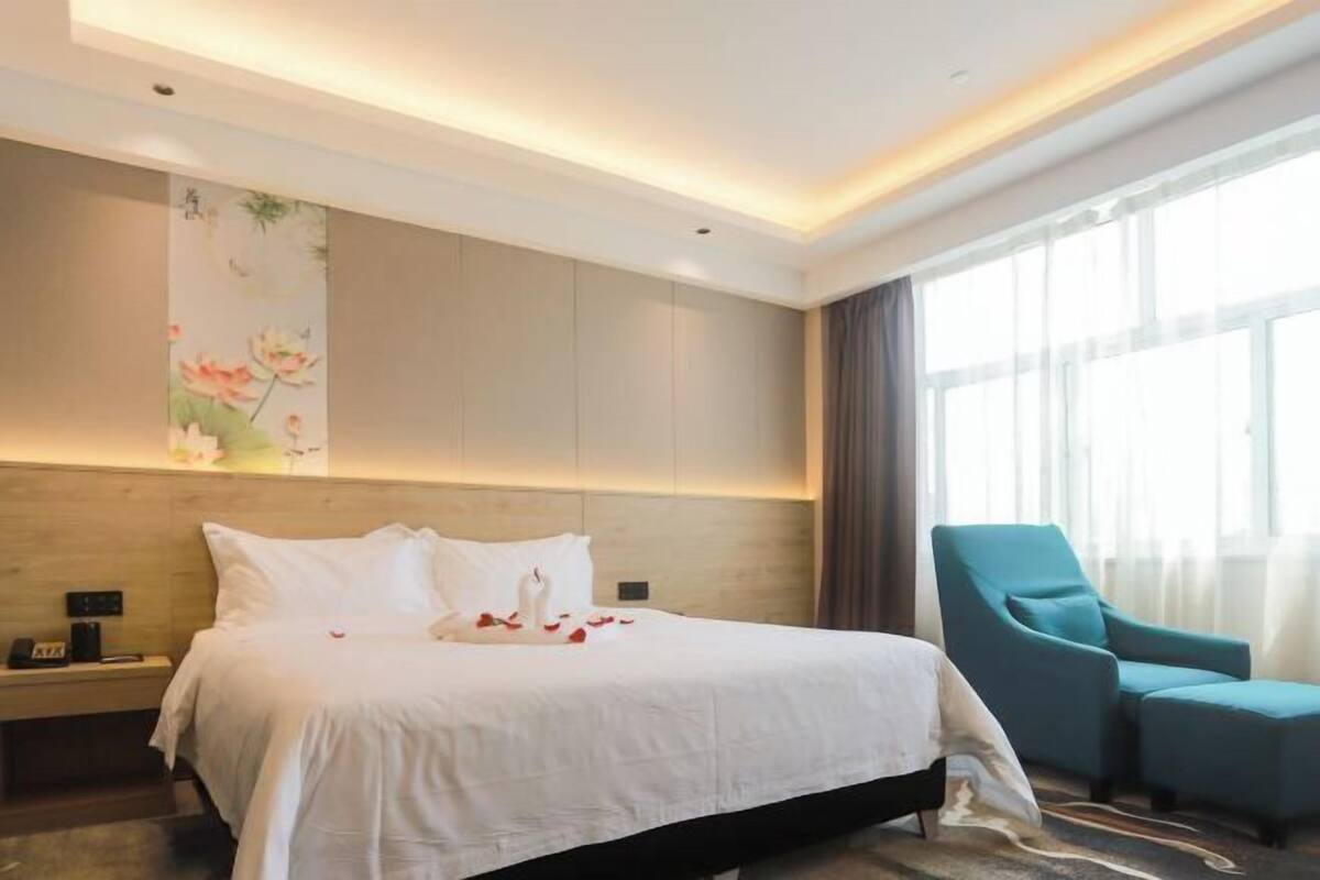 Una habitación de hotel con una cama grande, una mesita de noche, una silla y un cuadro floral en la pared.