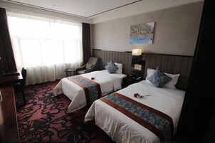 Una habitación de hotel con dos camas, un escritorio, una silla y un cuadro en la pared.
