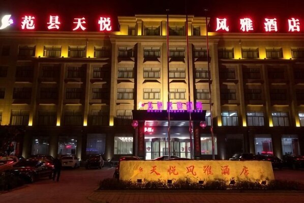 A hotel facade with illuminated signage, a central entrance, and a large sign in front. - Tianyue Fengya Hotel (Fan County)