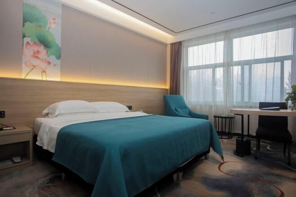 Une chambre d’hôtel avec un lit, un bureau, une chaise et une grande fenêtre.
