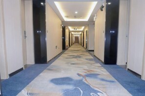 A hotel hallway with carpeted floors, doors numbered 311 and 312, and a long corridor leading to an elevator. - Tianyue Fengya Hotel (Fan County)