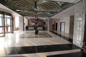 A hotel lobby with a reception desk, a decorative centerpiece, and a patterned floor.