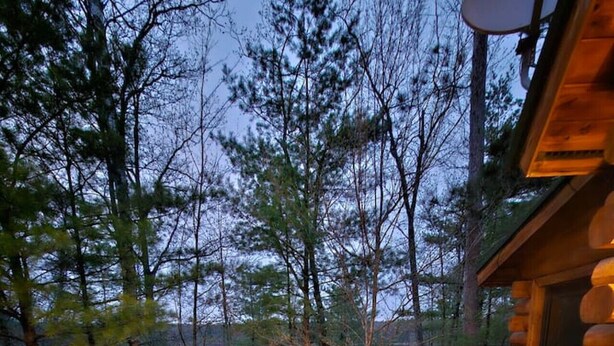A deck with Adirondack chairs, a fire pit, and a view of a forested area. - Private lakefront escape for unforgettable group getaways (Cable)