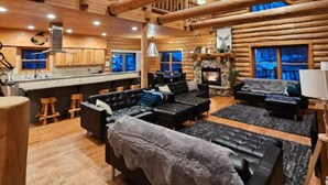 A spacious log cabin interior with a kitchen, living area, and a fireplace. - Private lakefront escape for unforgettable group getaways (Cable)