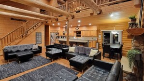 A spacious living area with a fireplace, a dining table, and a kitchen in the background. - Private lakefront escape for unforgettable group getaways (Cable)
