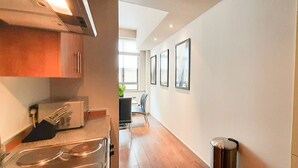A modern kitchen with stainless steel appliances, a dining area with chairs, and framed pictures on the wall. - 1-bed Apartment in City of London (London)