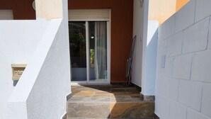 Un escalier menant à une porte dotée d’un panneau de verre, des murs blancs et un sol carrelé.