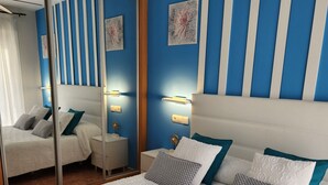 Een hotelkamer met een groot bed, een spiegel, een nachtkastje en een wand met verticale strepen.
