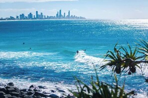 Eine Küstenstadtlandschaft mit freiem Blick auf das Meer und einem Surfer im Wasser.