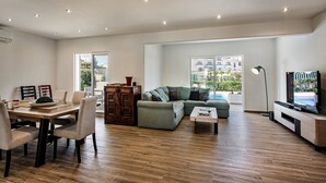 A modern living room with a dining area, a sofa set, a coffee table, and a television. - Silva (Albufeira)