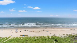 Una playa con sombrillas, una torre de salvavidas y una orilla arenosa.