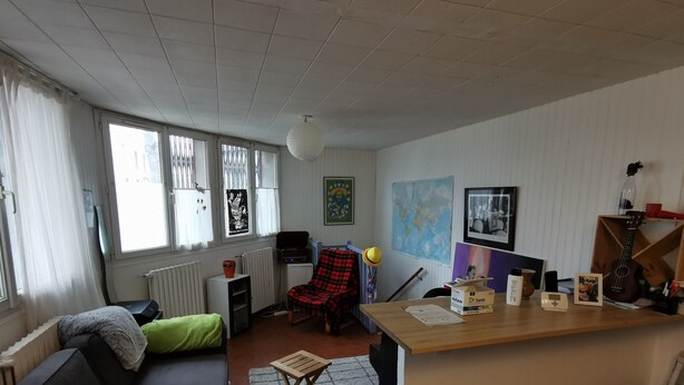 A living room with a sofa, a chair, a small table, and a wooden desk.