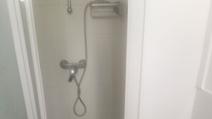 A bathroom with a glass shower enclosure, a white sink, and a handheld showerhead.