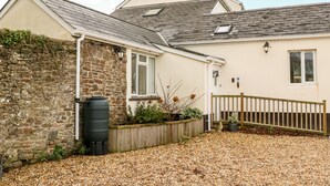 A house with a stone wall, a wooden fence, and a gravel driveway. - Littleham Court Cottage (Bideford)