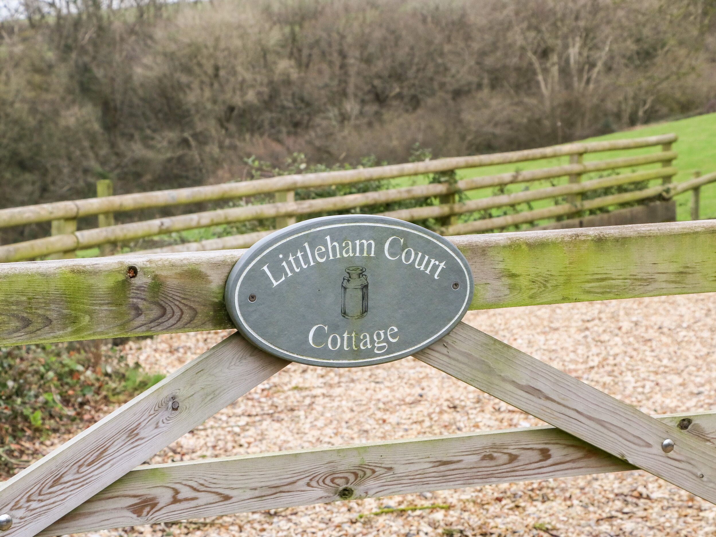 A sign on a wooden gate that reads "Littleham Court Cottage."
