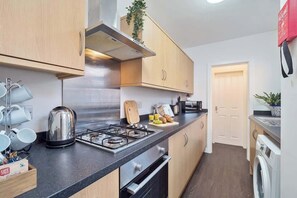 Kitchen features a stainless steel kettle, cutting board, and washing machine.