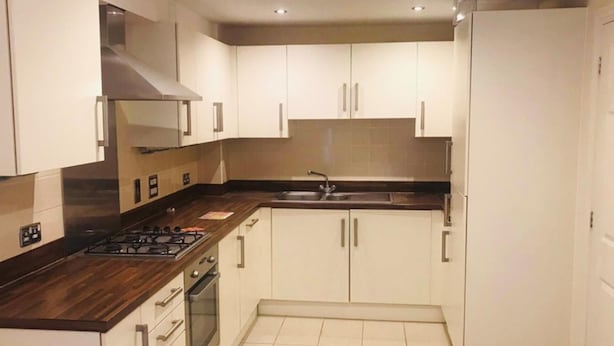 A modern kitchen with white cabinets, a stainless steel sink, and a gas stove.