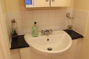 A bathroom sink with a glass bottle of liquid soap, a metal faucet, and a glass jar on the countertop. - 3 Bed Lego Themed Home - Sleeps 6 - Wifi, Parking (Slough)