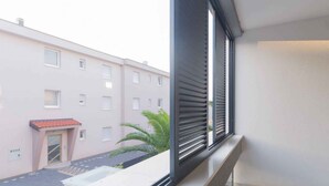 A balcony with a view of a pink building and a palm tree. - Holiday apartment with garage (Njivice)
