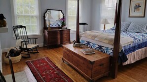 A bedroom with a four-poster bed, a wooden dresser, a rocking chair, and a red rug. - Masters rental - Historic federal in the heart of Edgefield county (Johnston)