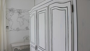 A room with a white wardrobe, a small table, and a world map on the wall. - Enter another world... (Châtel-Guyon)