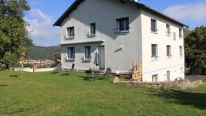 A two-story building with a flat roof, multiple windows, and a small patio area with outdoor furniture. - Enter another world... (Châtel-Guyon)