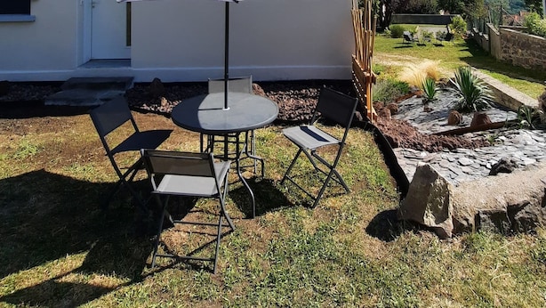 A two-story building with a flat roof, a small porch with a table and chairs, and a view of the countryside. - Enter another world... (Châtel-Guyon)